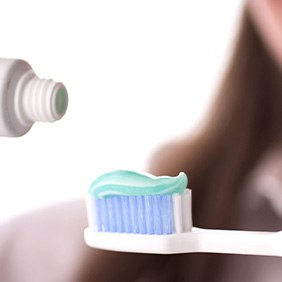 Lady applies toothpaste to brush