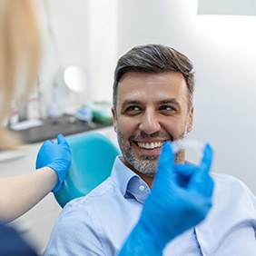 Man in dental chair smiling at dentist handing him Invisalign