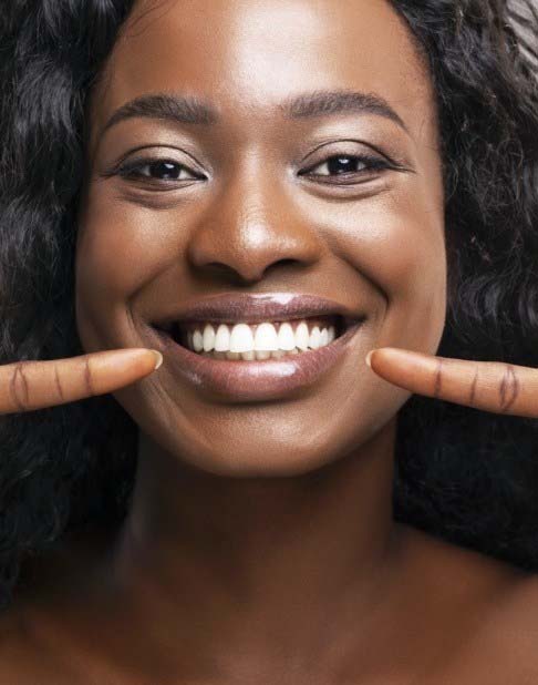 Patient pointing to smile after teeth whitening