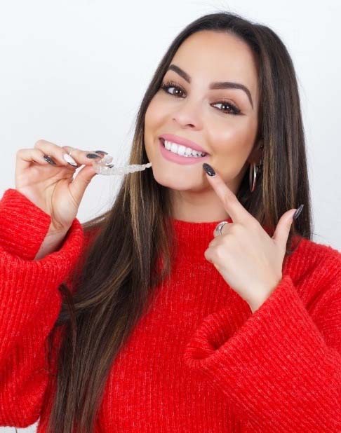 Smiling patient holding an Invisalign tray