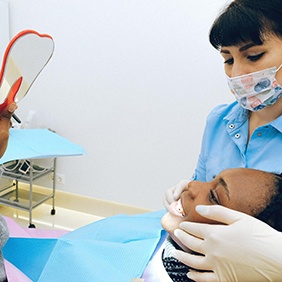 Woman looking in dental mirror at cosmetic consultation