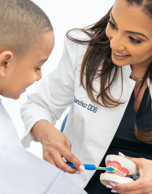 Doctor Sanchez teaching young patient to brush teeth