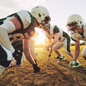 Athletes in green and white uniforms playing football on field