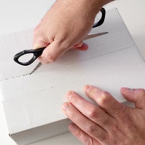 Man using scissors to open white box