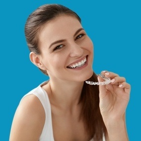 Smiling woman holding an Invisalign clear braces tray