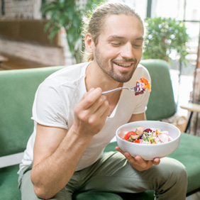Man sitting on couch eating a salad
