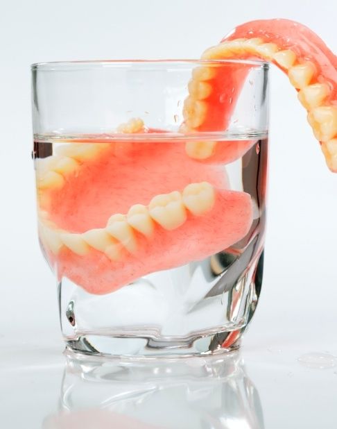 Full set of dentures in a glass of water