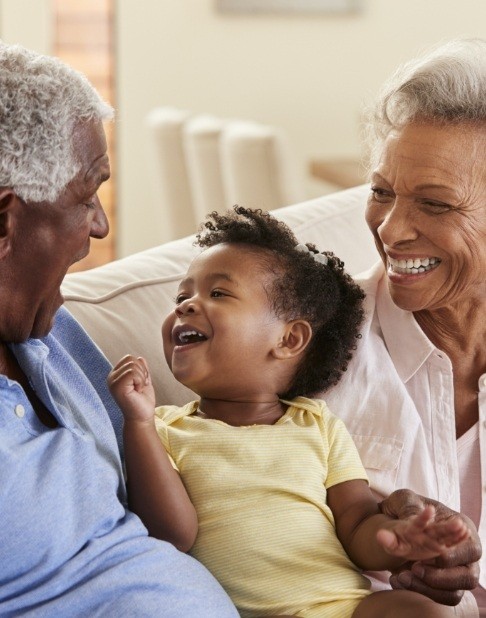 Grandparents smiling at grandchild after full mouth reconstruction