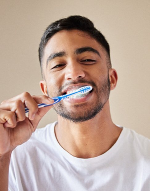 Bearded man brushing his teeth and smiling