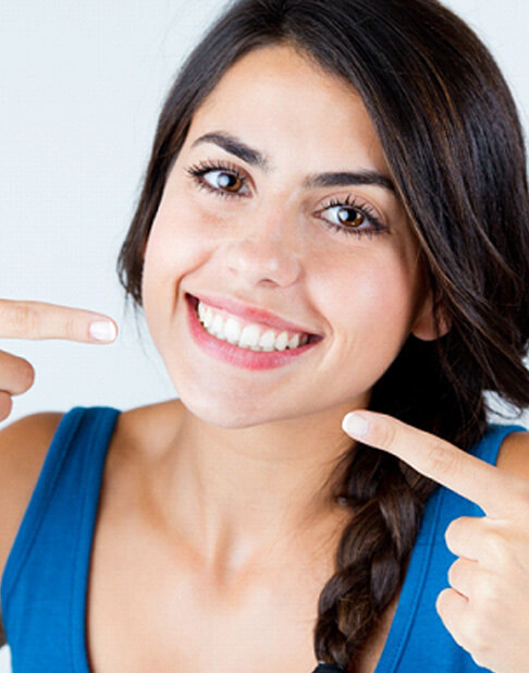 woman smiling and pointing to her teeth