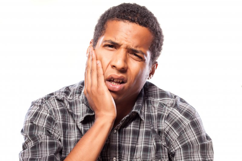 patient with dental emergency holding their cheek