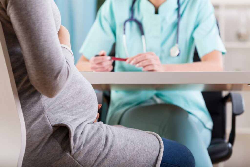 A pregnant woman discussing dental implants with her dentist